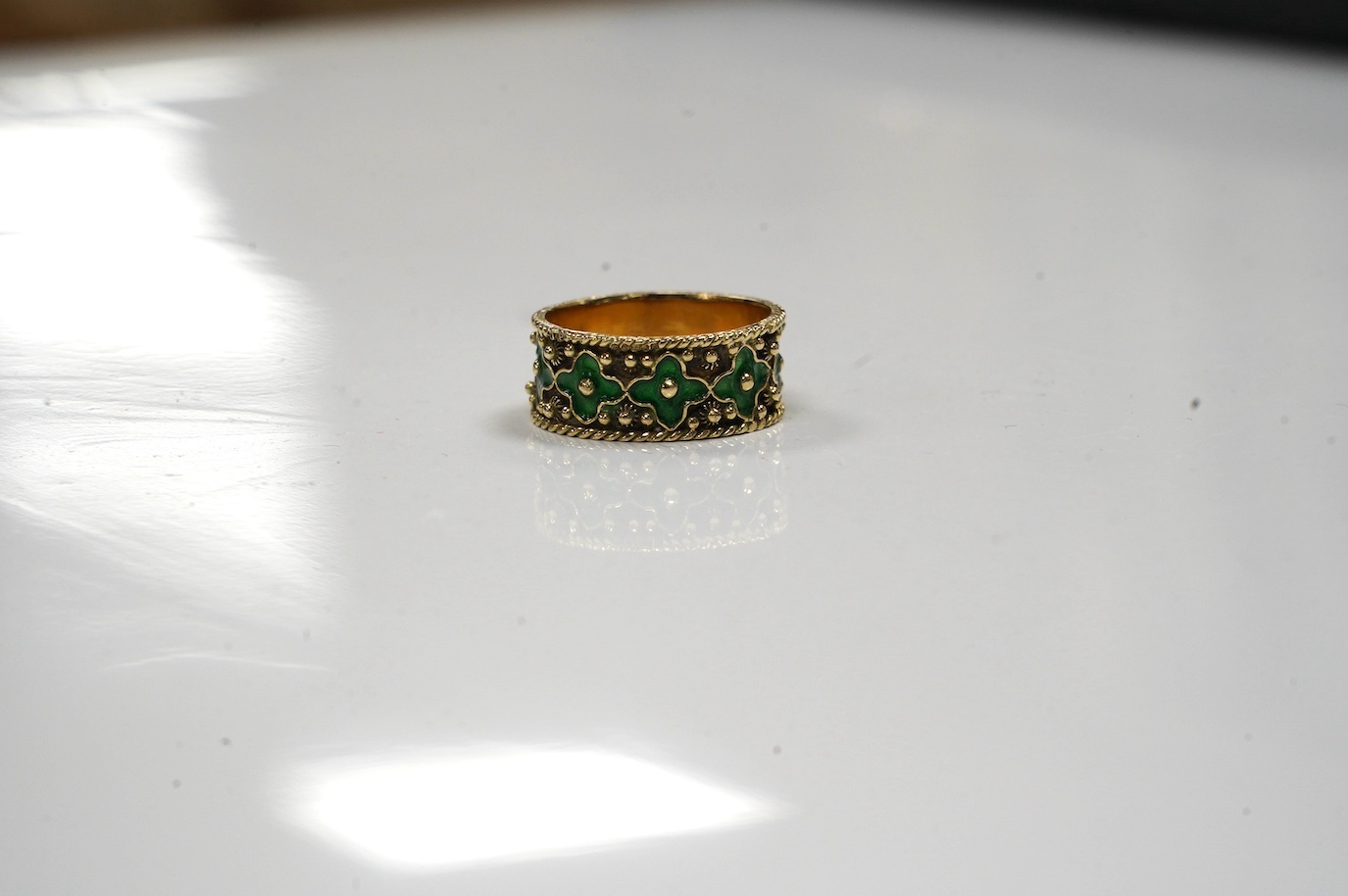 A 14ct gold and green enamel set flower head band, size O/P, gross weight 4.7 grams. Condition - fair